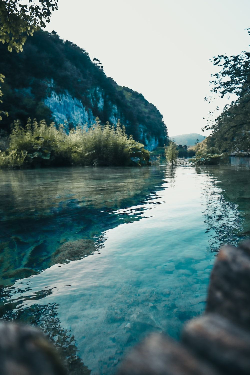 A serene body of water surrounded by trees and mountains. - River