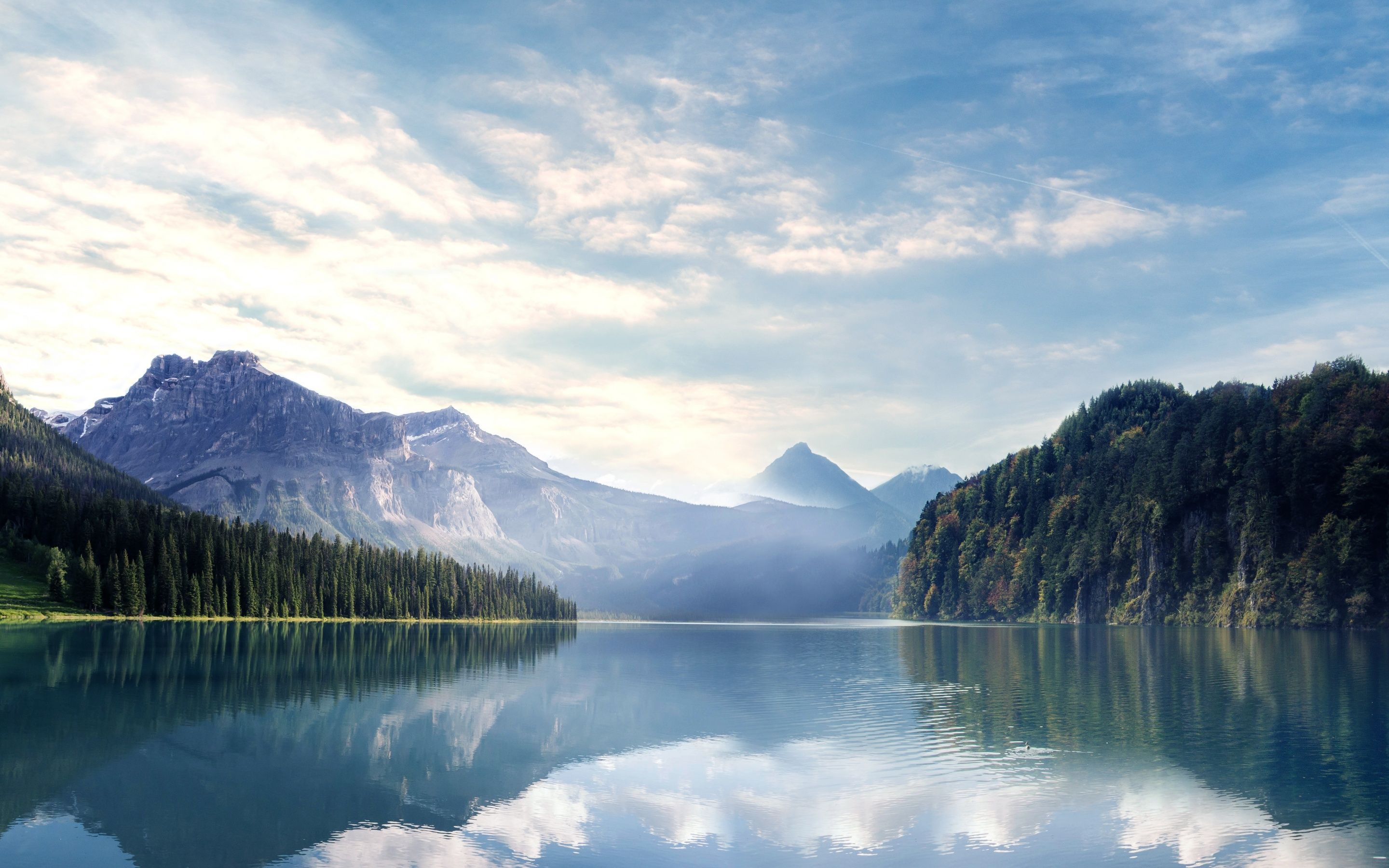 A serene lake surrounded by forested mountains. - River