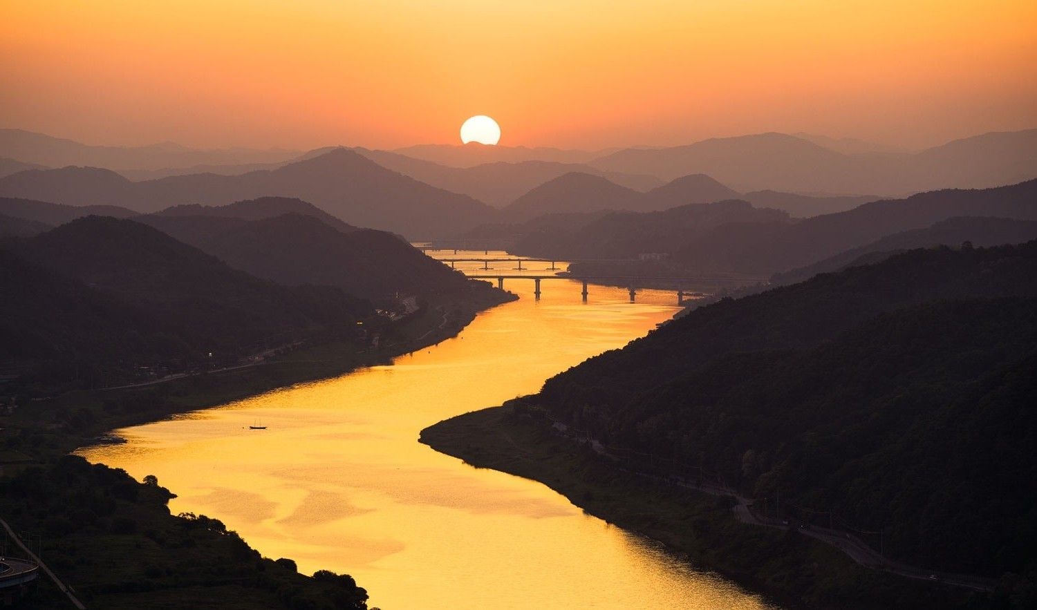 A sunset over a river surrounded by mountains - River