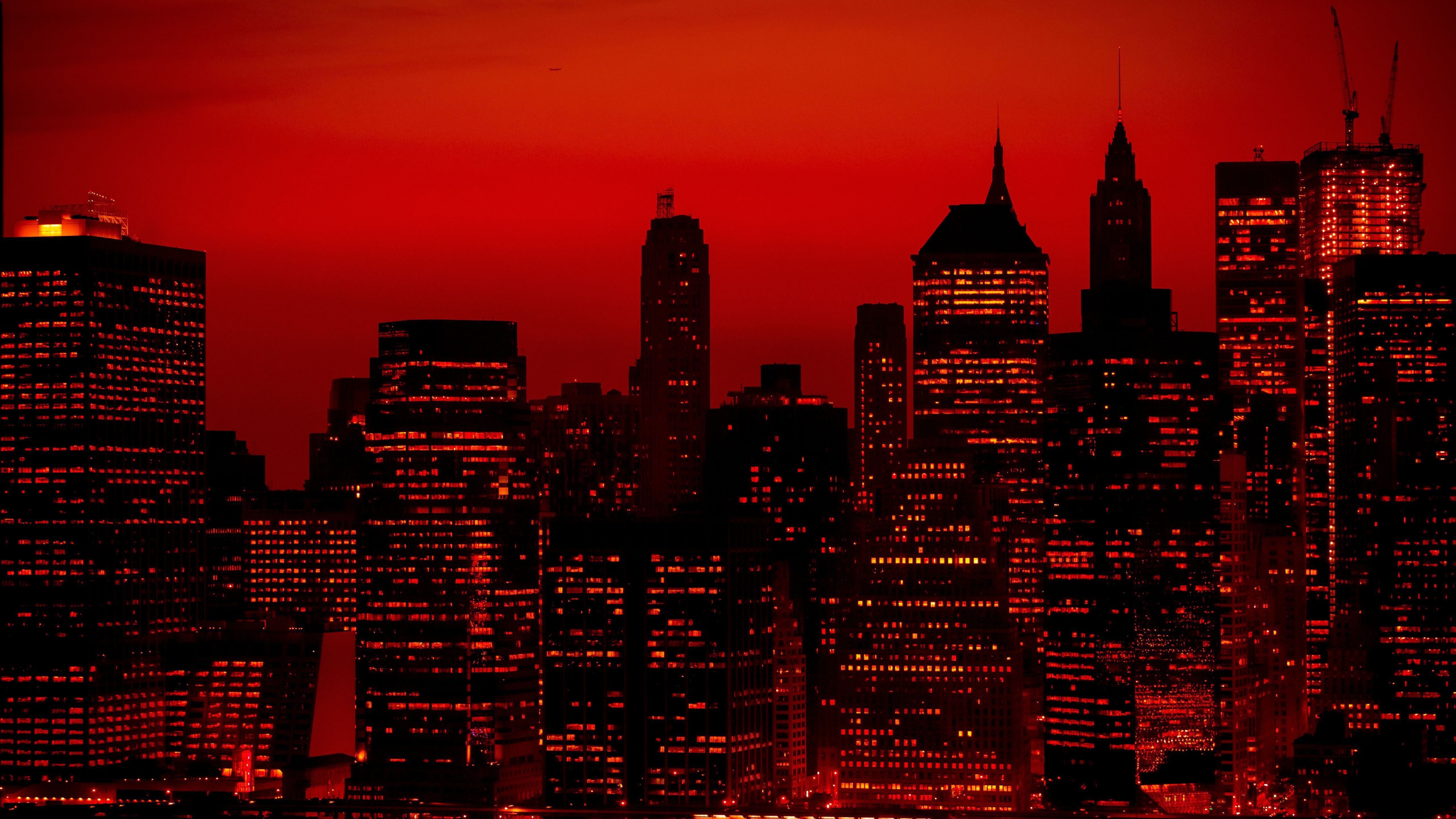 The image is a night time view of the Manhattan skyline with a red hue. - Cityscape