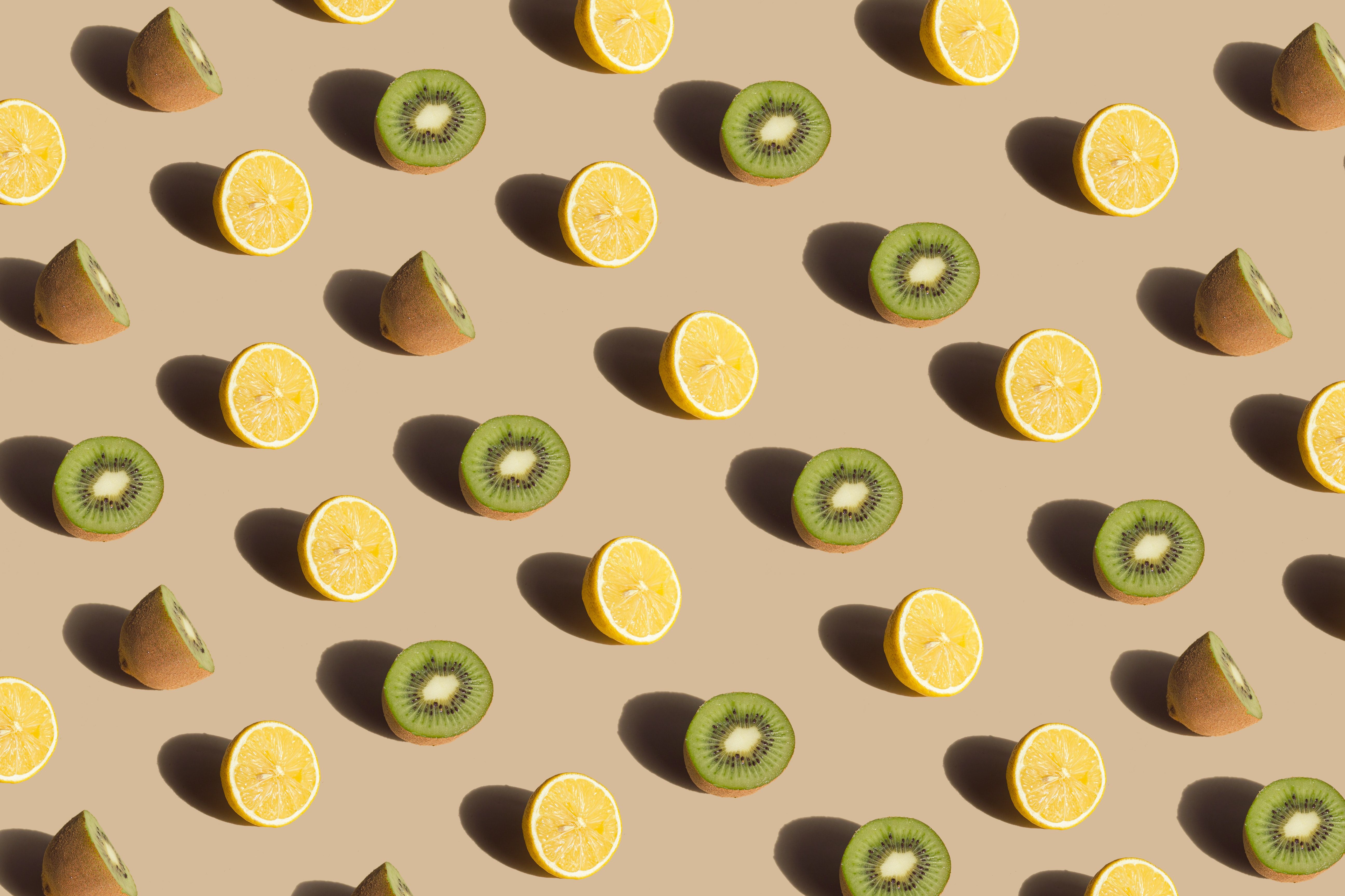 A pattern of猕猴桃 and lemon slices on a beige background - Kiwi