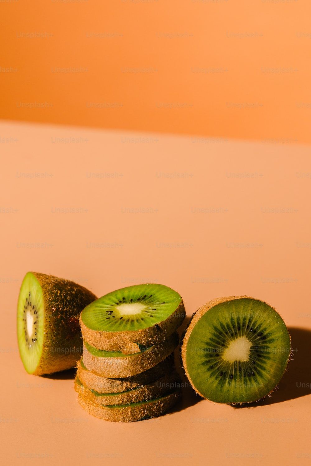 Sliced kiwi fruit on a pastel orange background - Kiwi