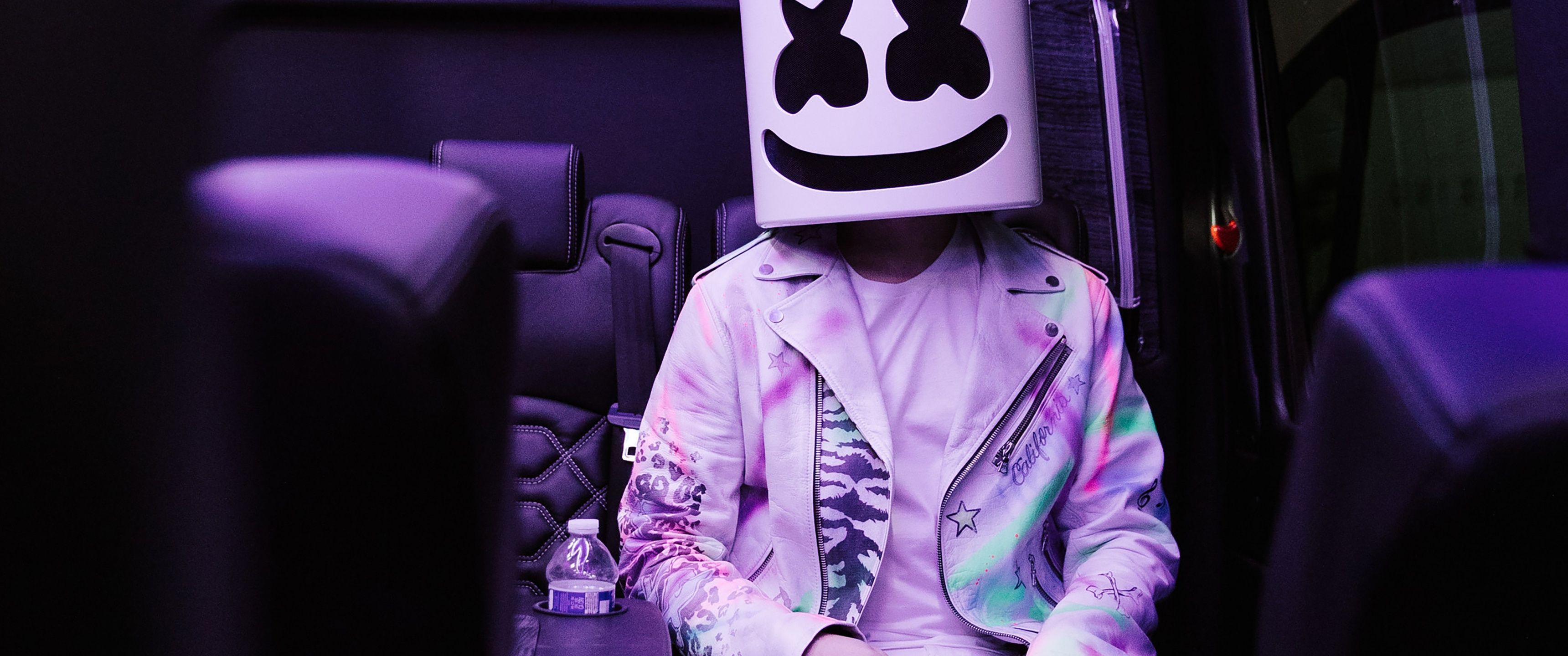 Marshmello sitting in a bus seat with a smiley face for a head - Marshmello