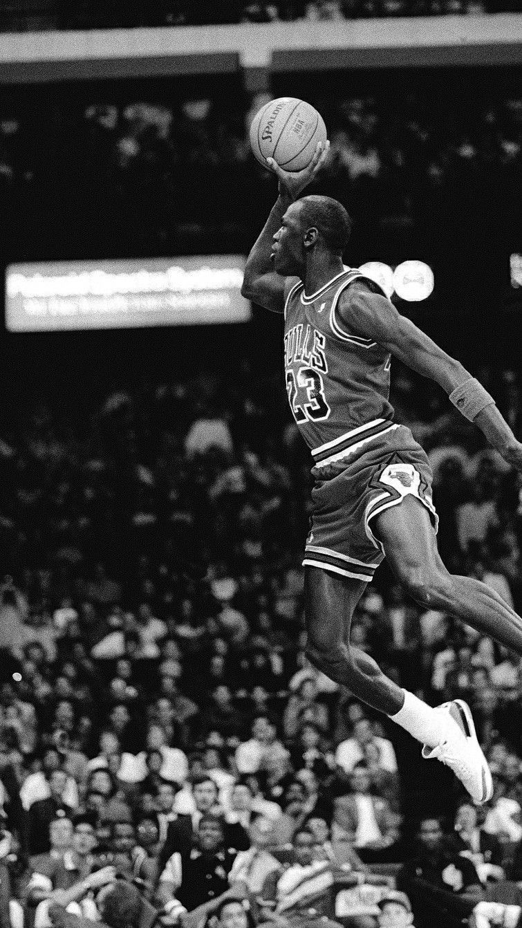 Michael Jordan jumping up in the air with a basketball in his hand. - Michael Jordan