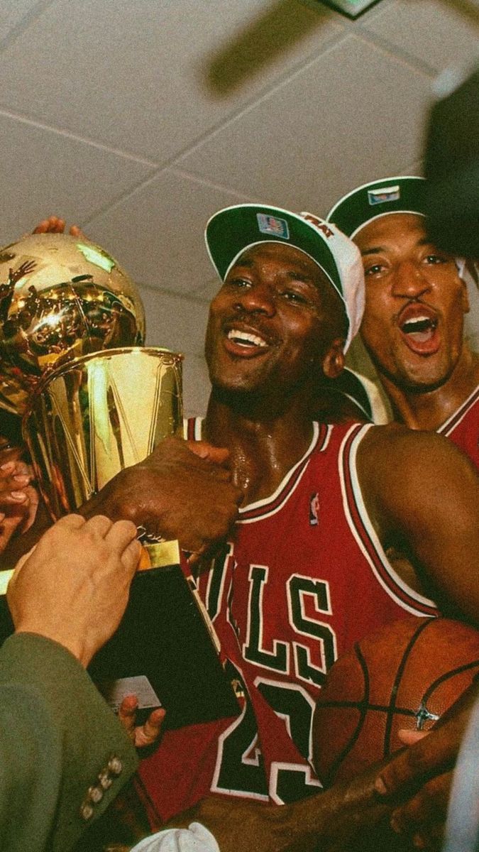 Michael Jordan holding the championship trophy while teammates look on. - Michael Jordan