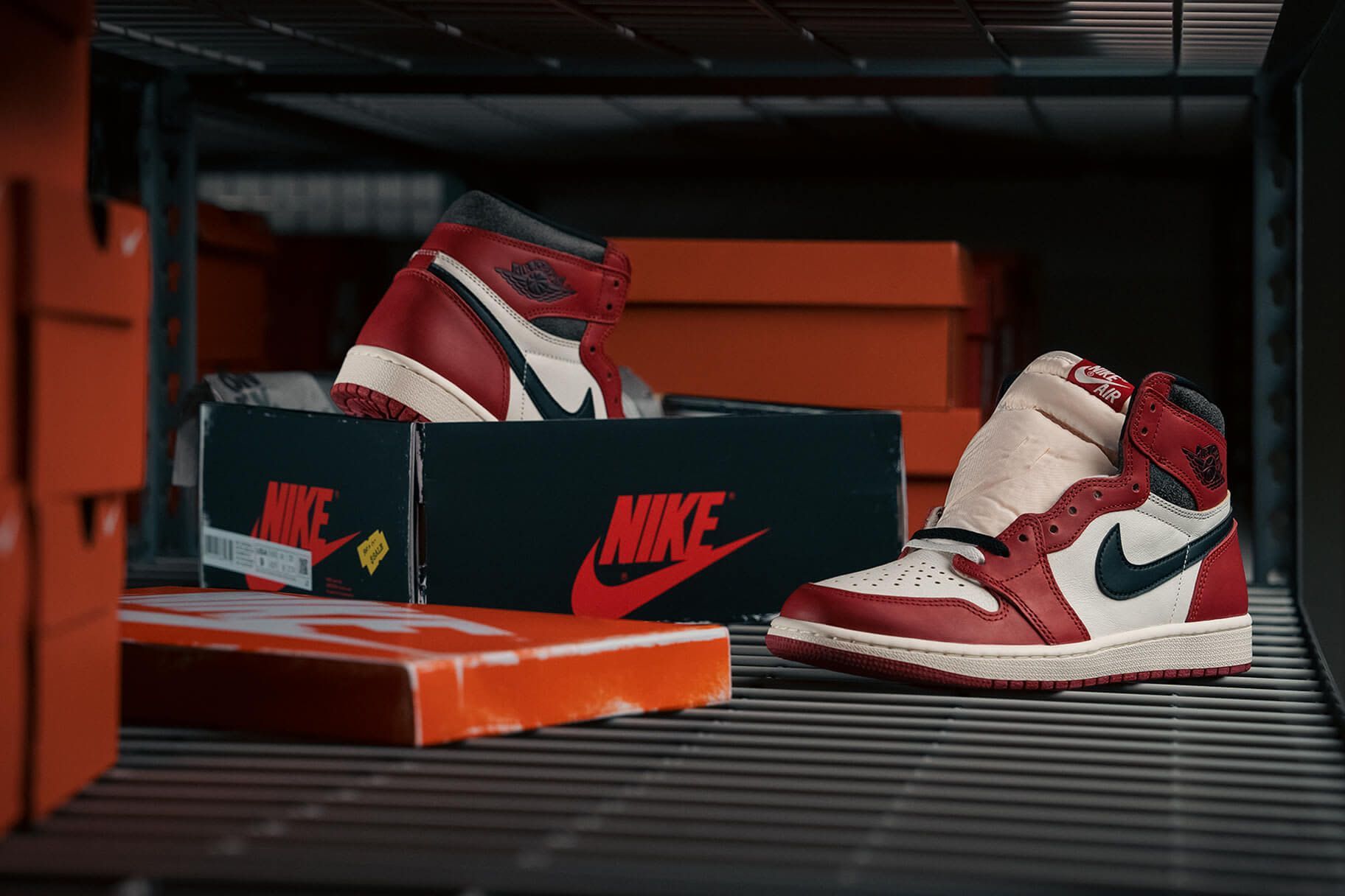 A pair of red and white Nike sneakers sit on a shelf next to their original box. - Air Jordan