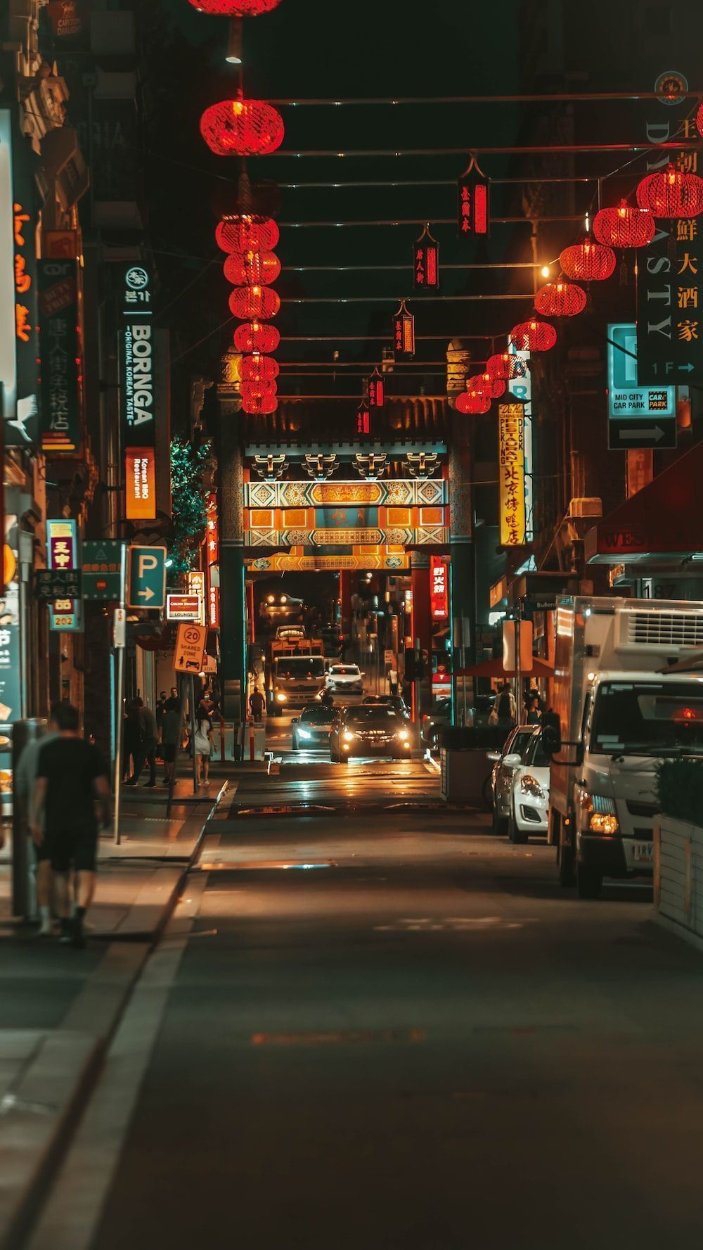 A city street at night with Chinese lanterns hanging above. - Chinese