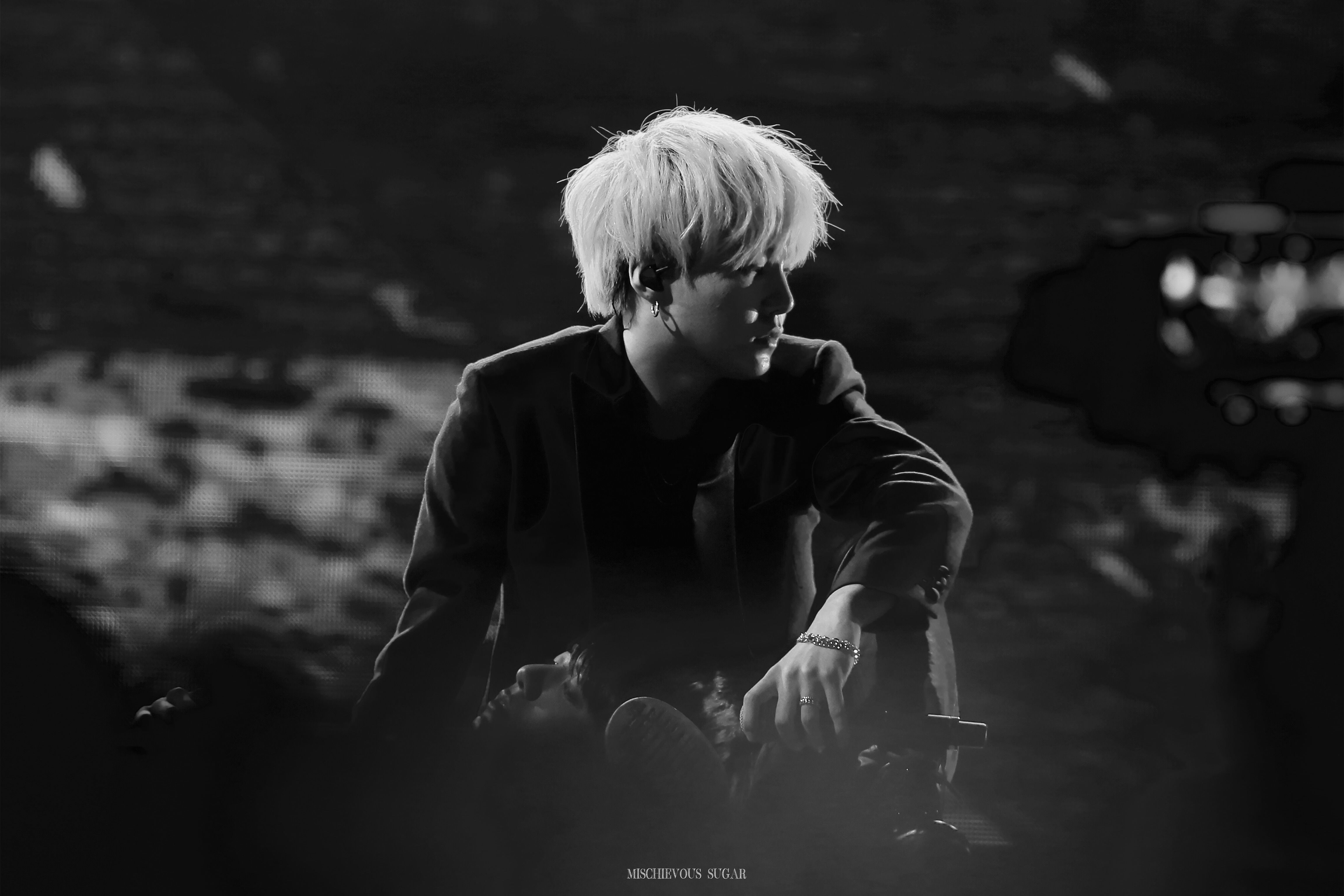 A man with white hair sitting down - Suga