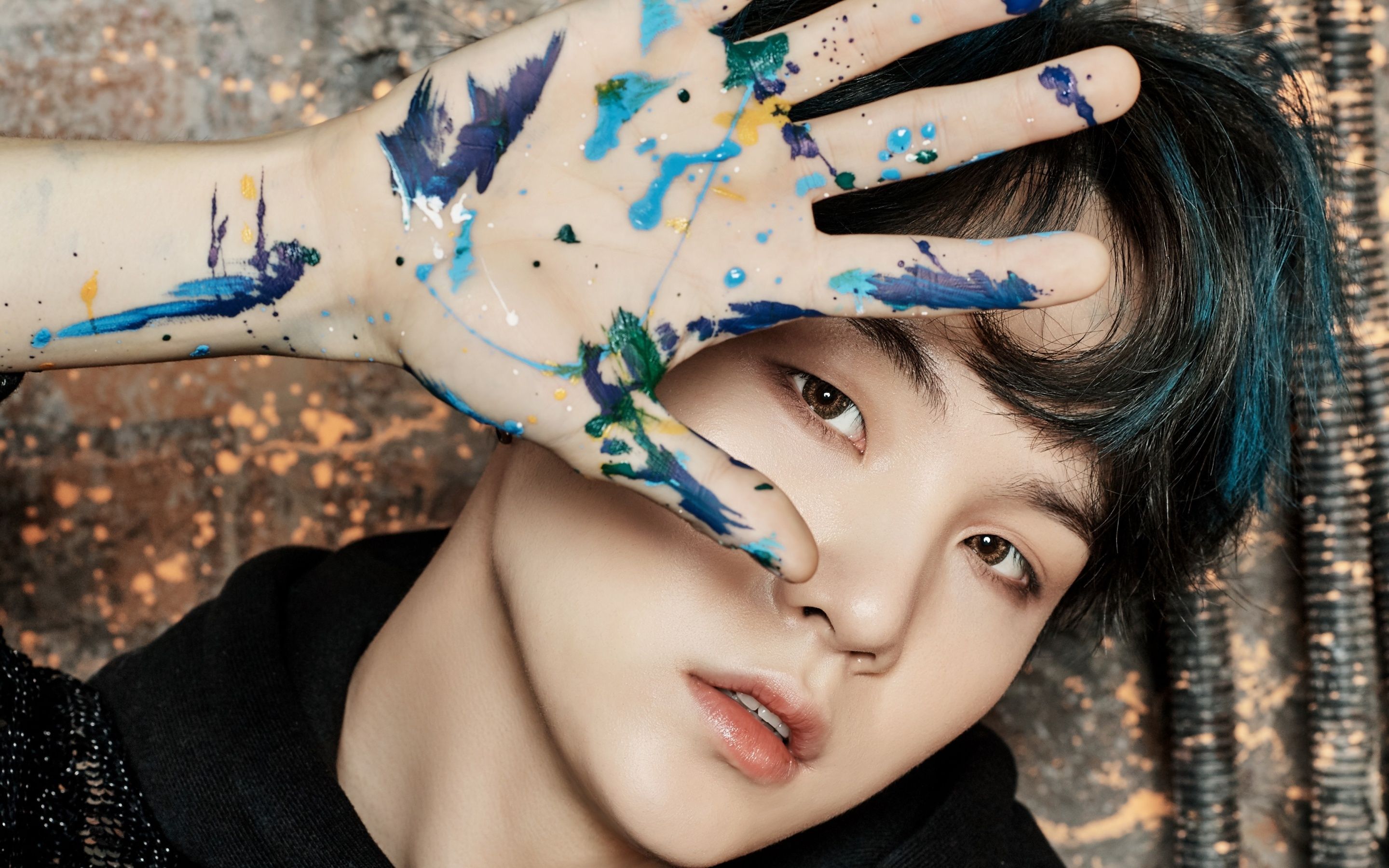 A young man with blue hair and paint on his hands - Suga