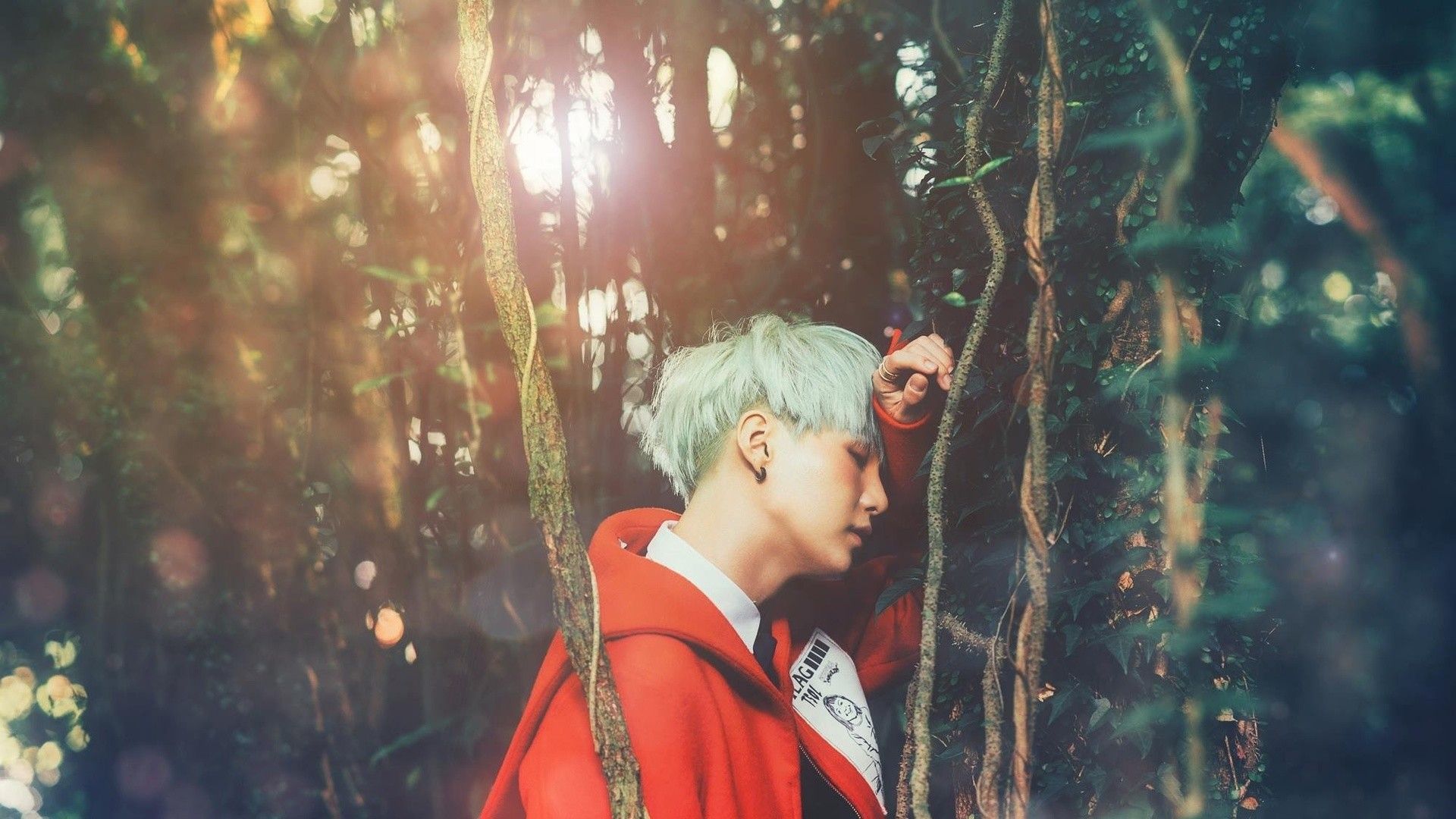 A person with green hair standing in a forest. - Suga