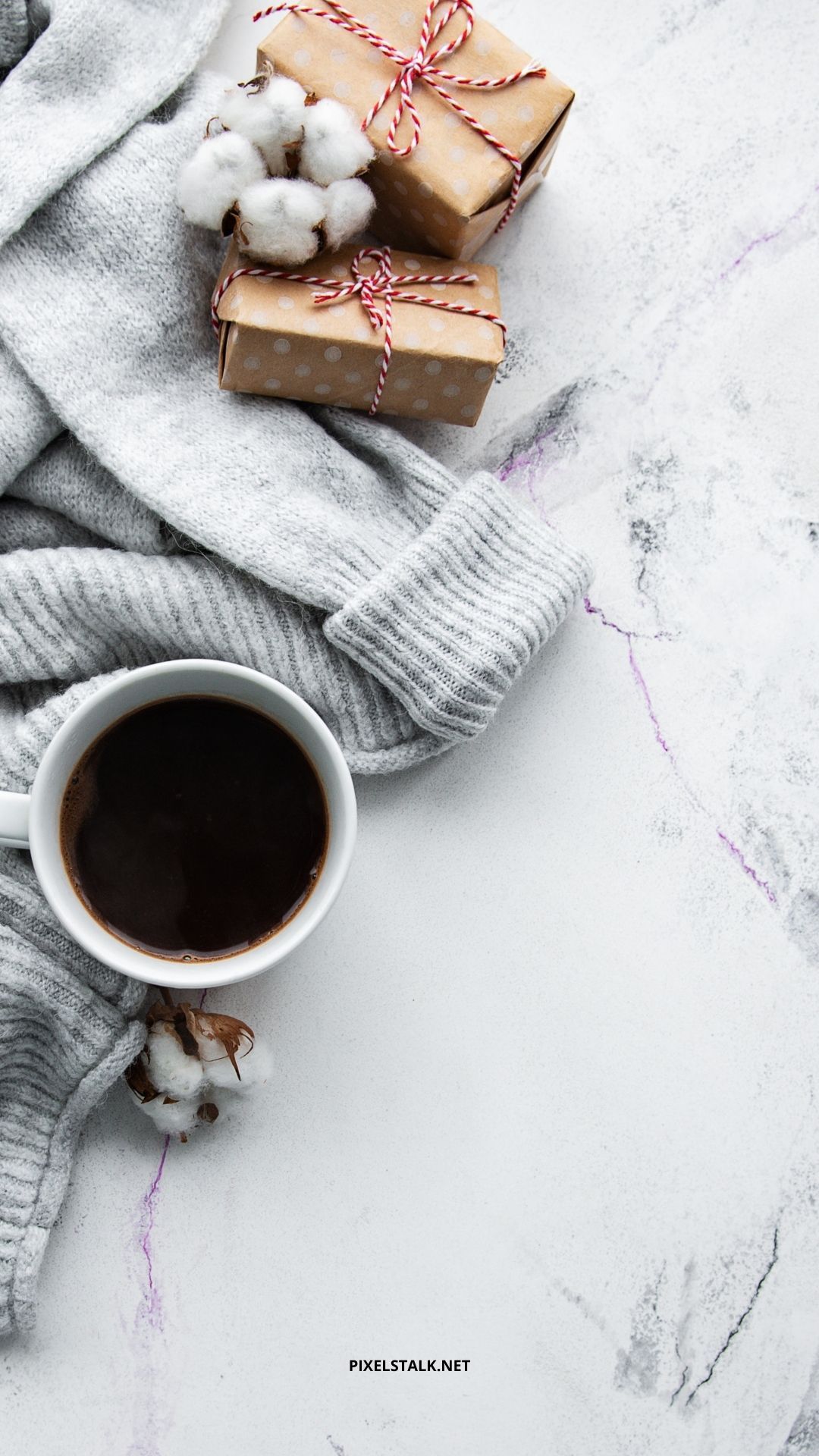 A cup of coffee, a sweater and two gift boxes on a white marble table - Cozy