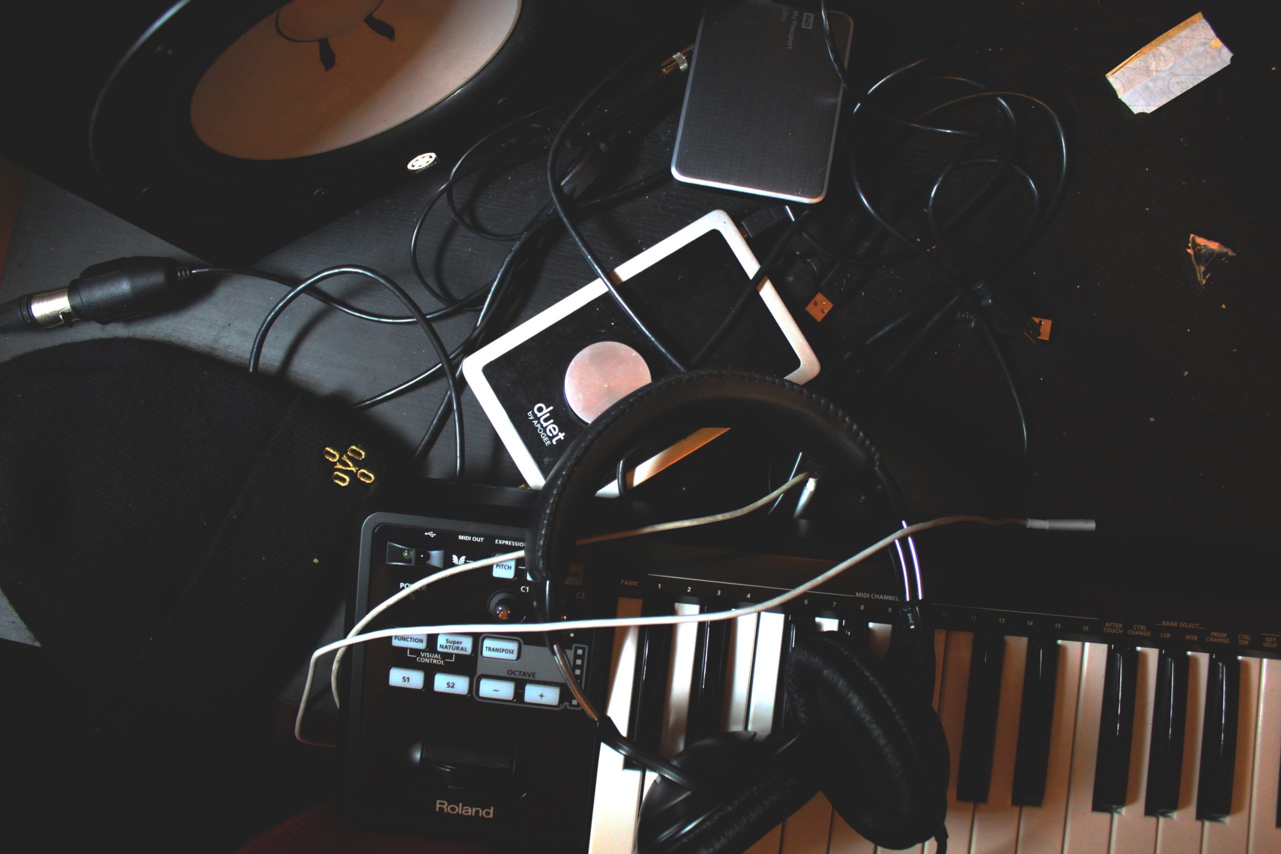 A keyboard, headphones and other electronic devices are on the table - Music, piano