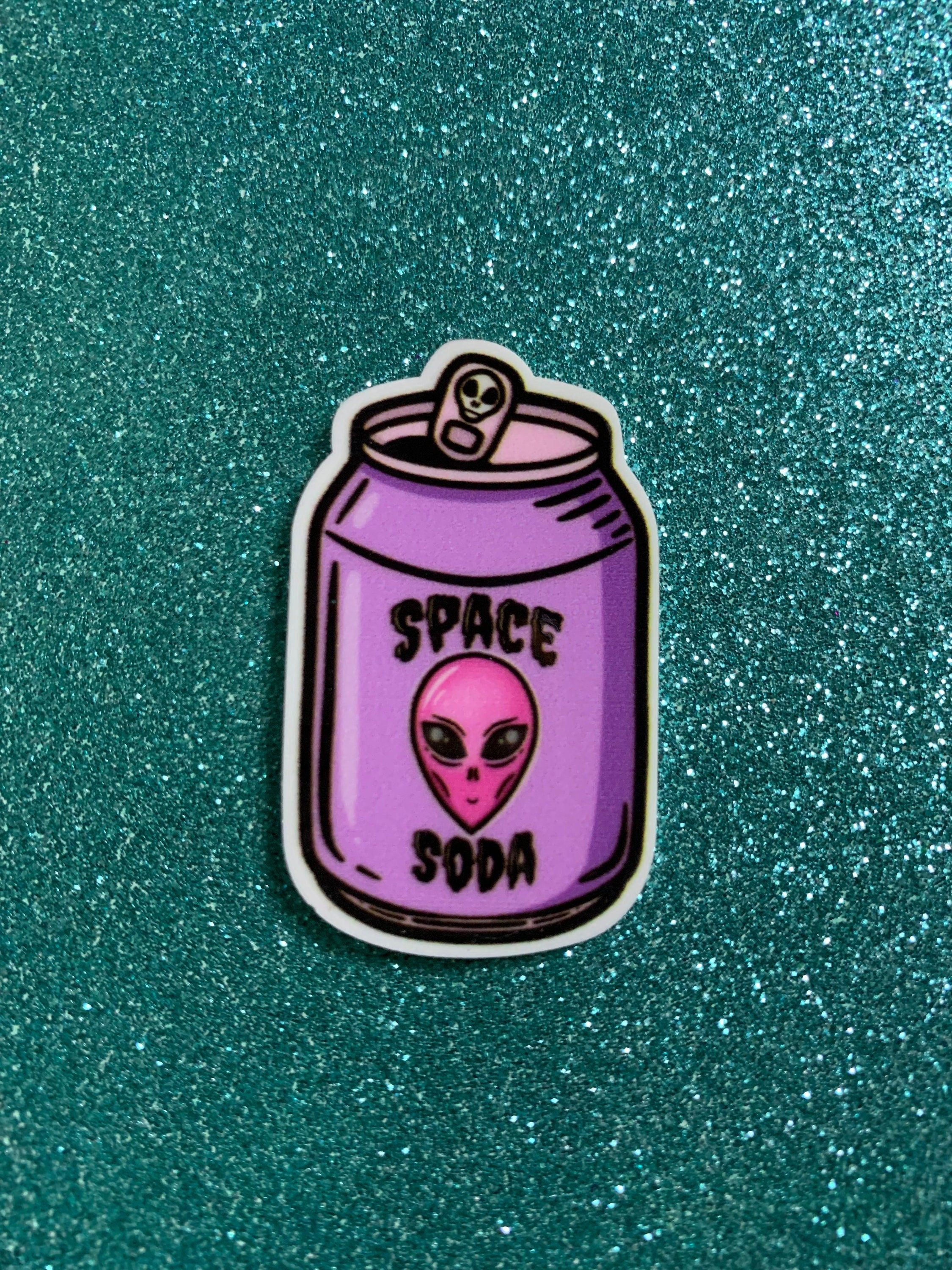 A sticker of a pink alien head on a purple background with the words 