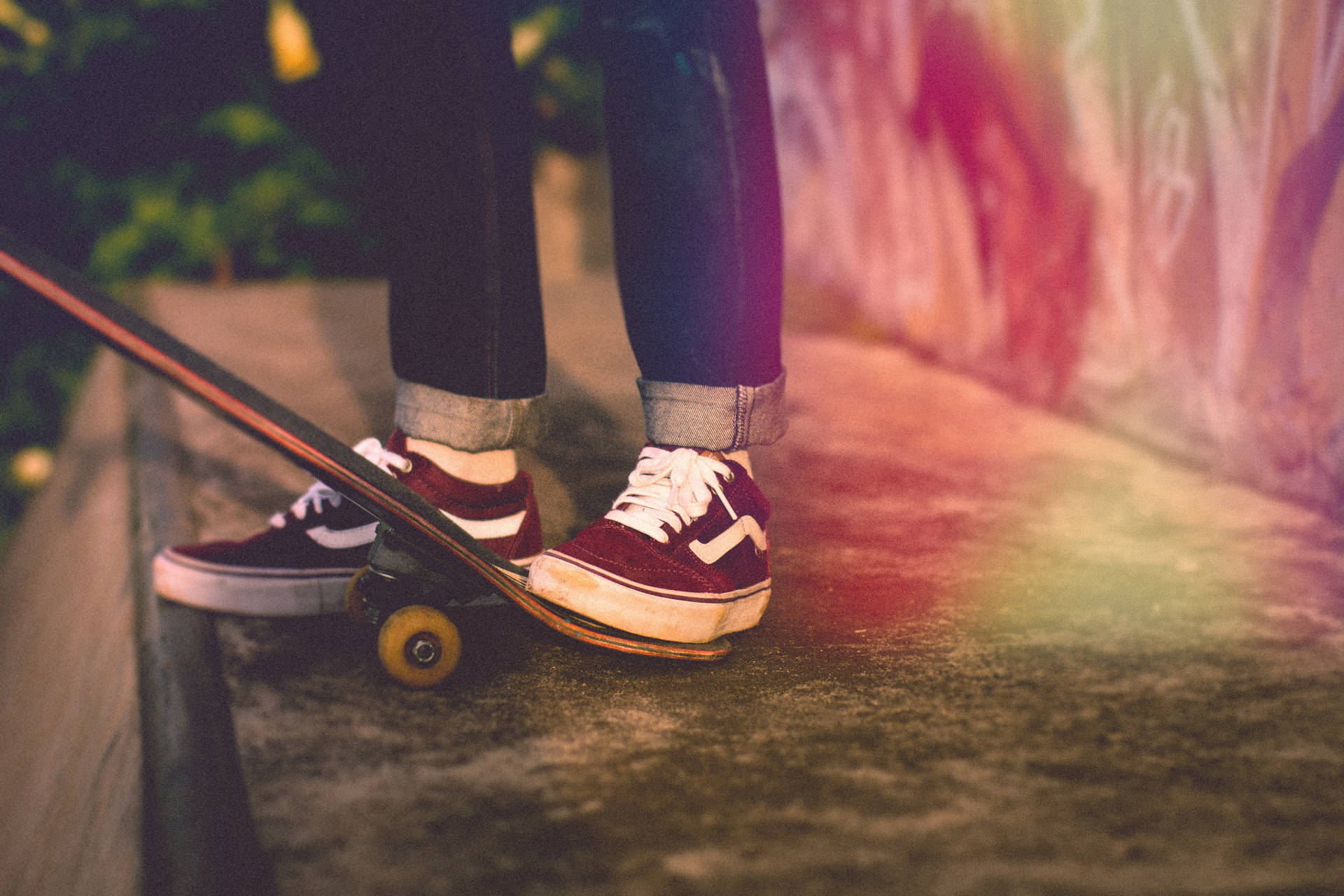 A person wearing Vans shoes is standing on a skateboard. - Vans