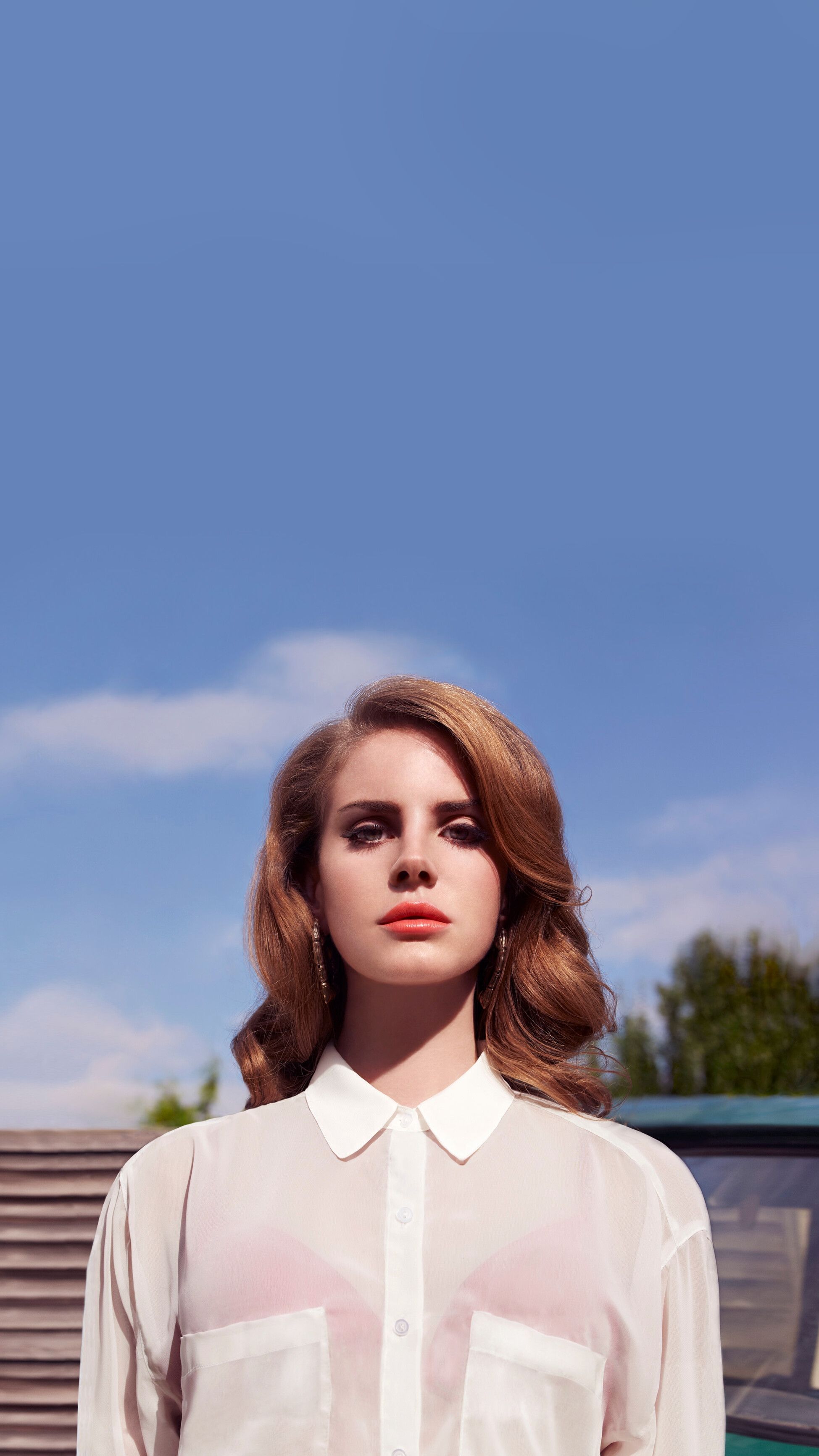 A woman with a white shirt and red lipstick standing in front of a car - Lana Del Rey
