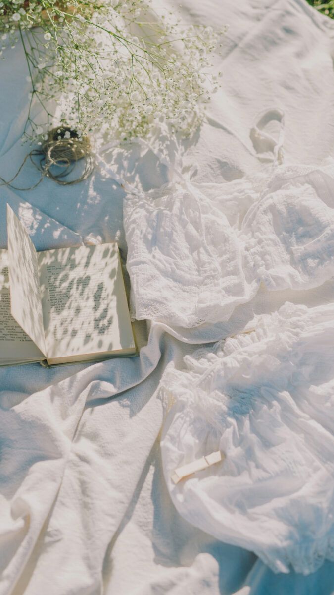 A book, a ring, and a bouquet of flowers on a white sheet. - Cottagecore