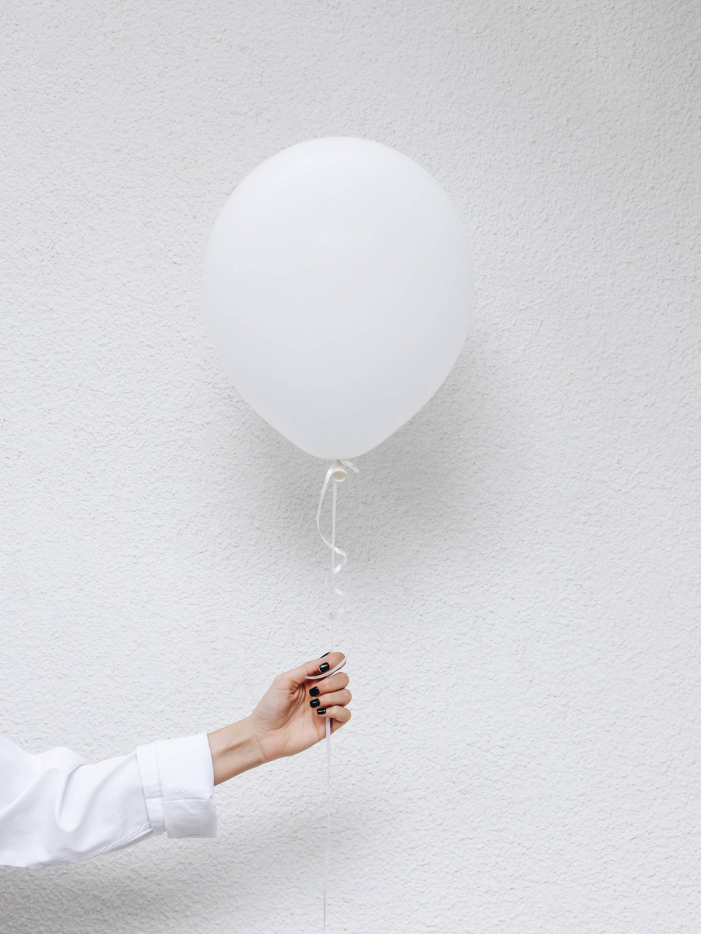 A woman's hand holding a white balloon - Balloons