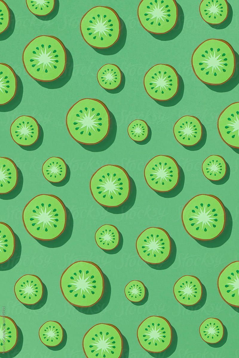 Pattern of paper kiwi slices on a green background. - Kiwi