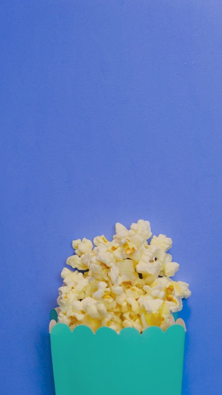 Popcorn scattered in stop motion on a blue background Stock Video