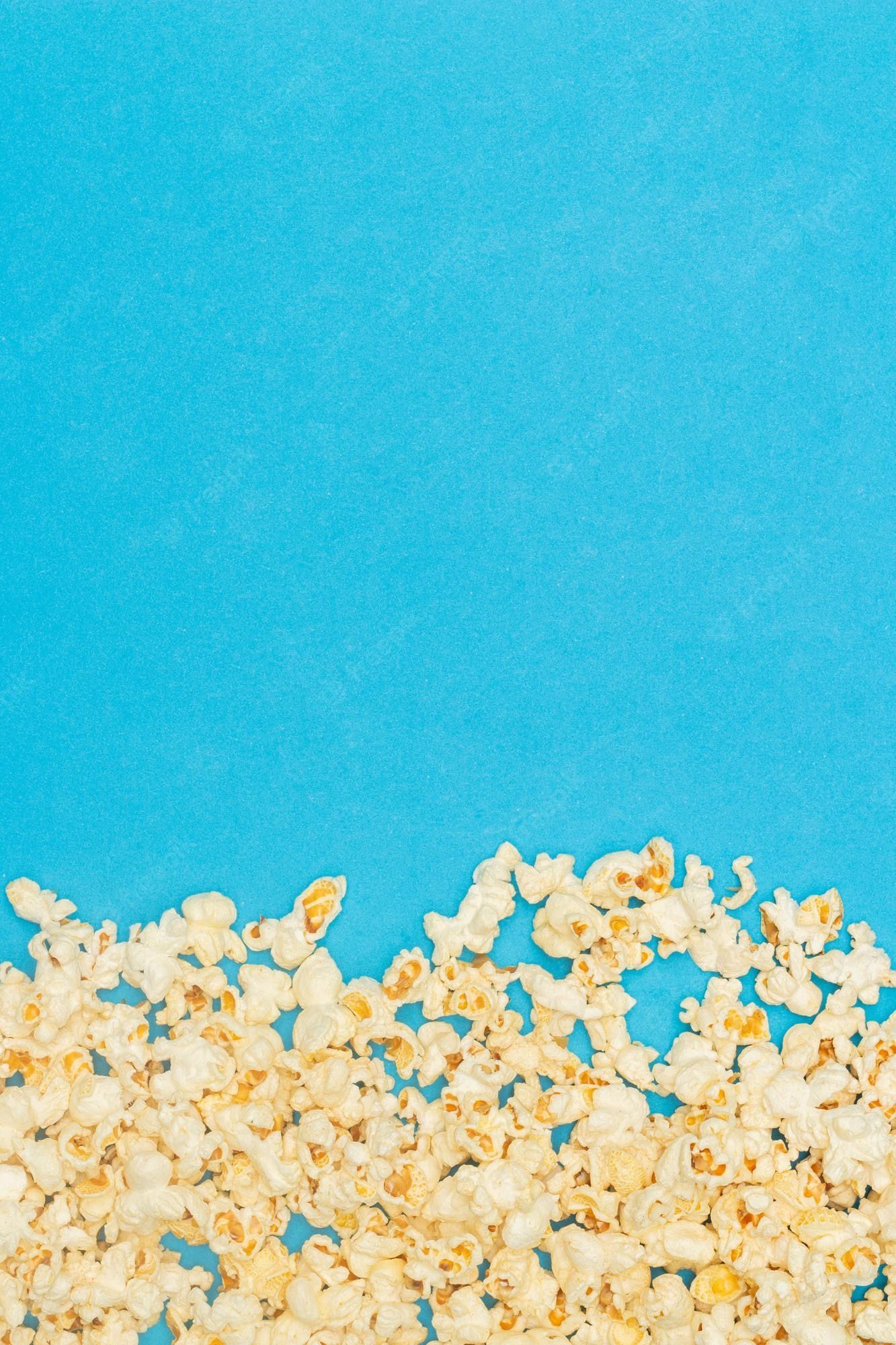 A blue background with a pile of popcorn in the foreground - Popcorn