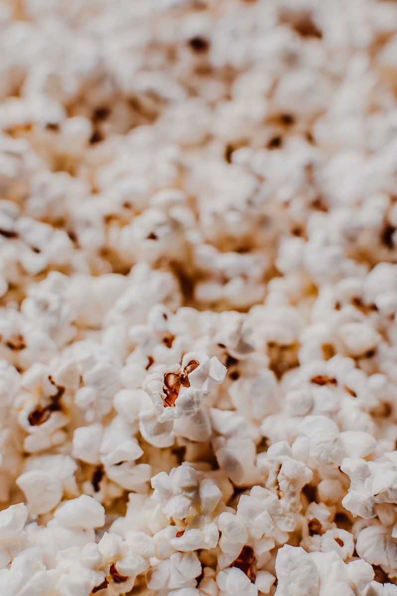 A close up of popcorn in a pile with a spoon in the middle. - Popcorn