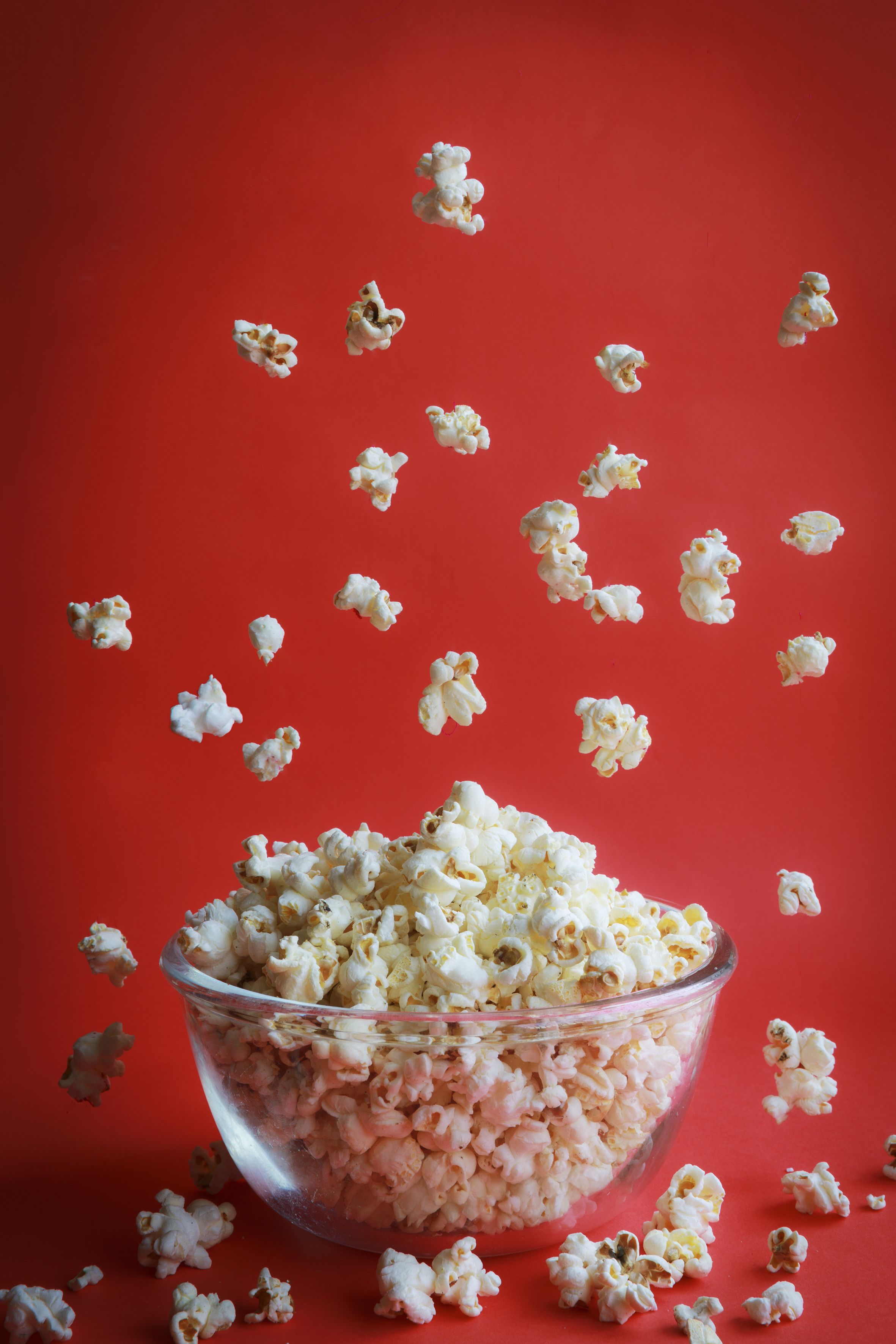 A bowl of popcorn with popcorn flying out of it. - Popcorn