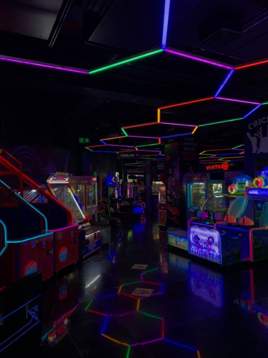The interior of an arcade with neon lights and games - Arcade