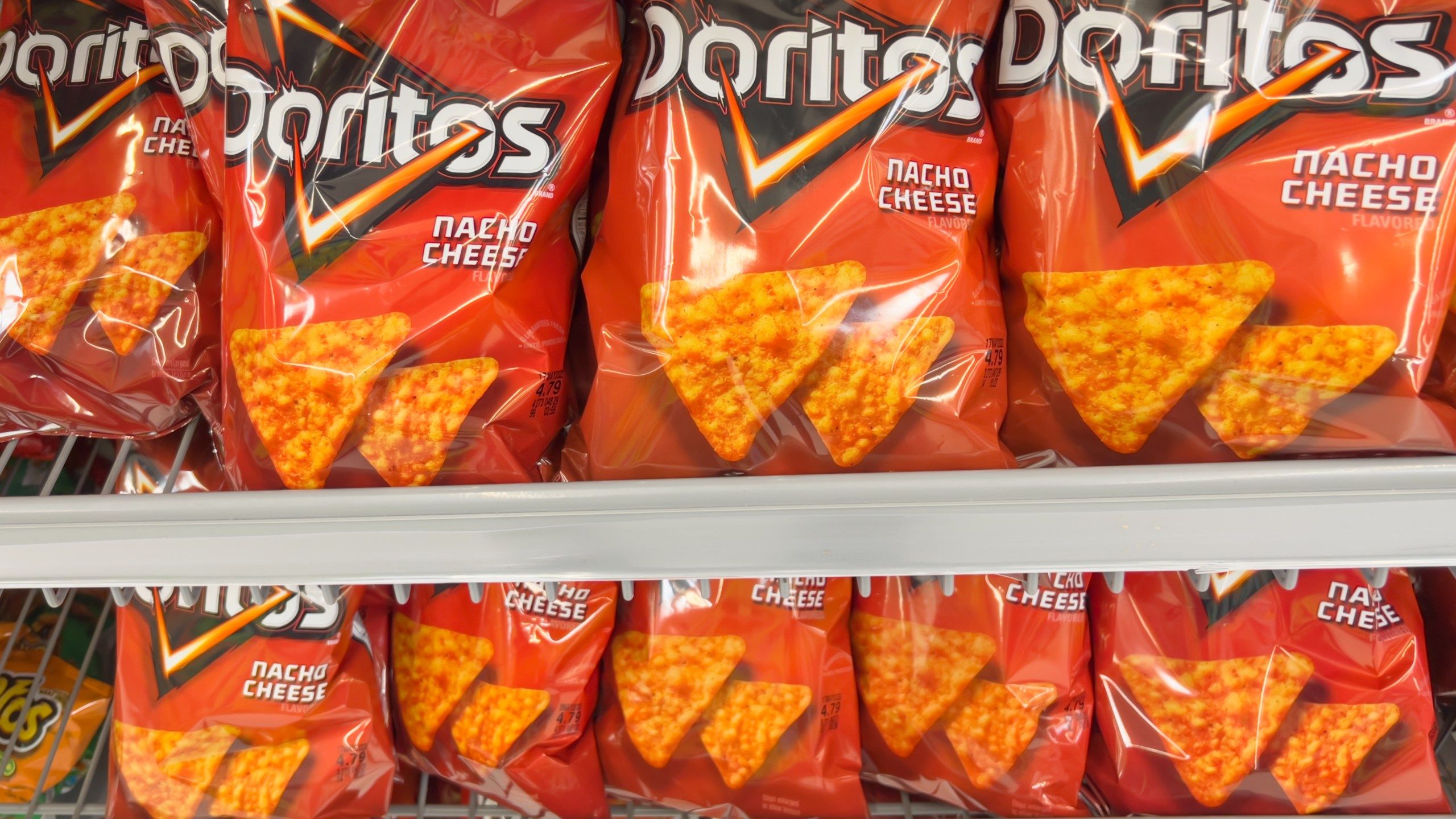 A shelf of bags of Doritos, a brand of snack chips produced by Frito-Lay. - Doritos