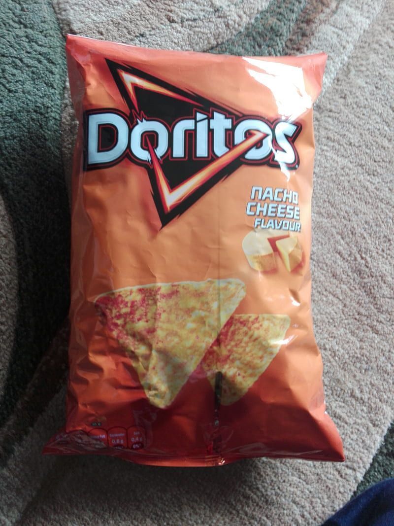 A bag of Doritos Nacho Cheese flavor lays on a carpeted surface. - Doritos