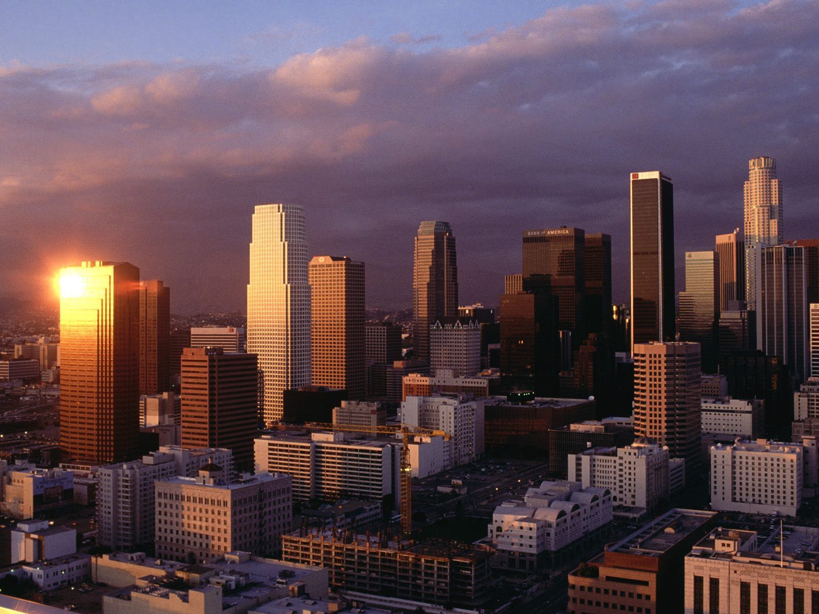 A city skyline with the sun setting in it - Los Angeles