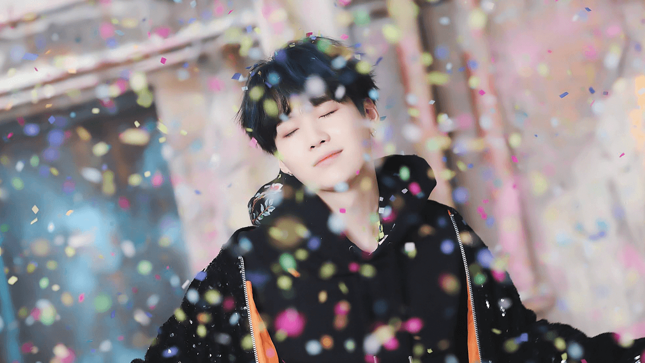 A person is standing in the middle of confetti - Suga