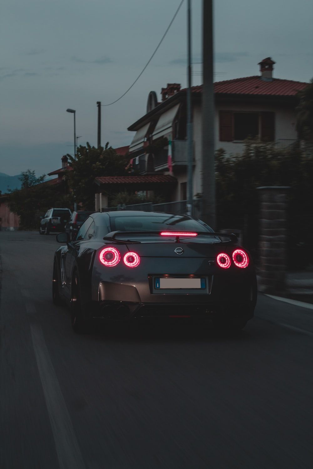 A black sports car with red lights driving down a street - Nissan Skyline