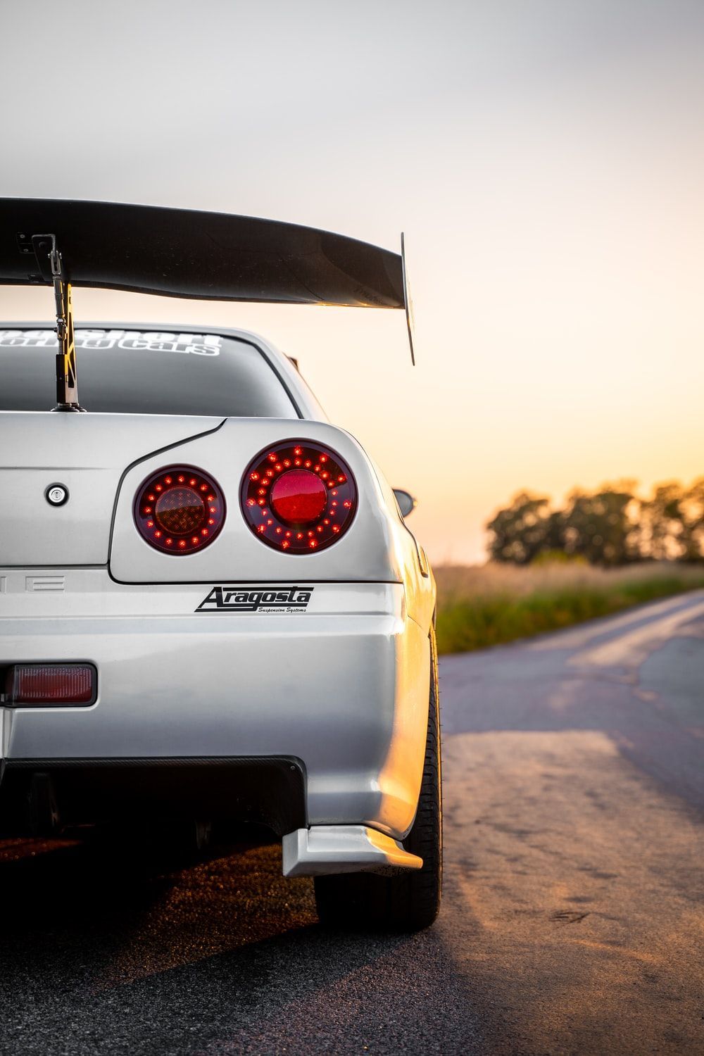 A white R34 GTR with a wing on the back. - Nissan Skyline