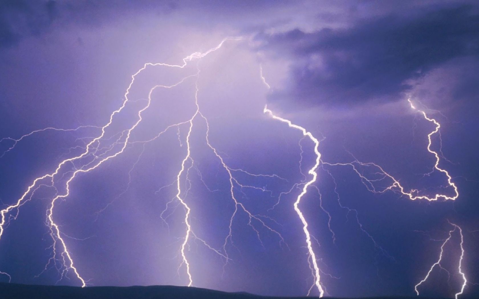 Multiple lightning bolts strike the ground in a purple sky. - Lightning