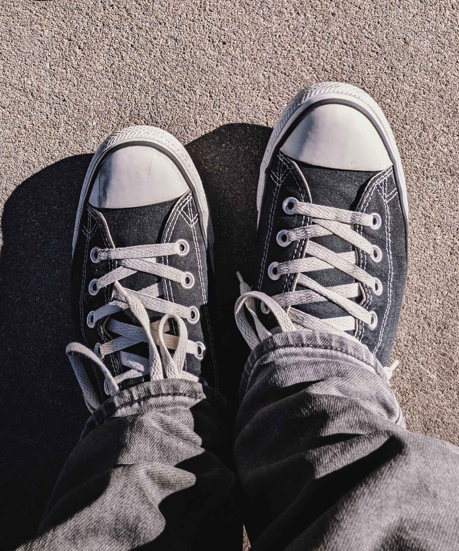 A person wearing jeans and black Converse sneakers - Converse