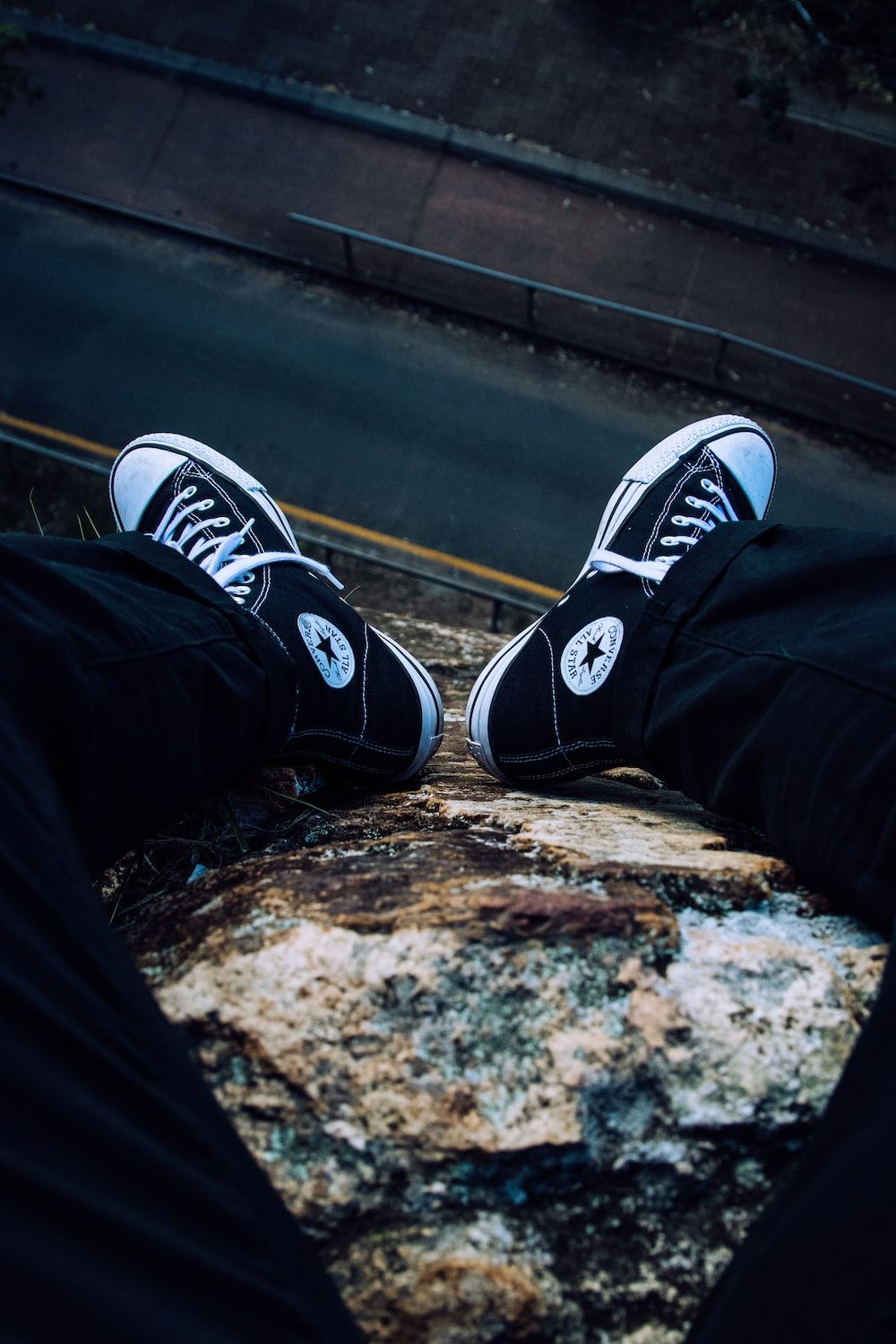 Person in black pants wearing black and white converse all star high tops photo