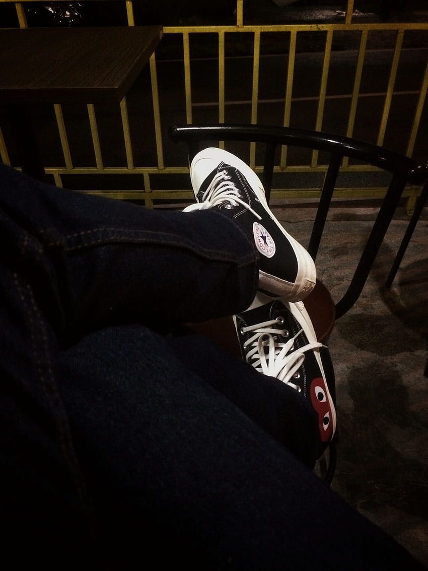 A person wearing black and white converse sneakers. - Converse