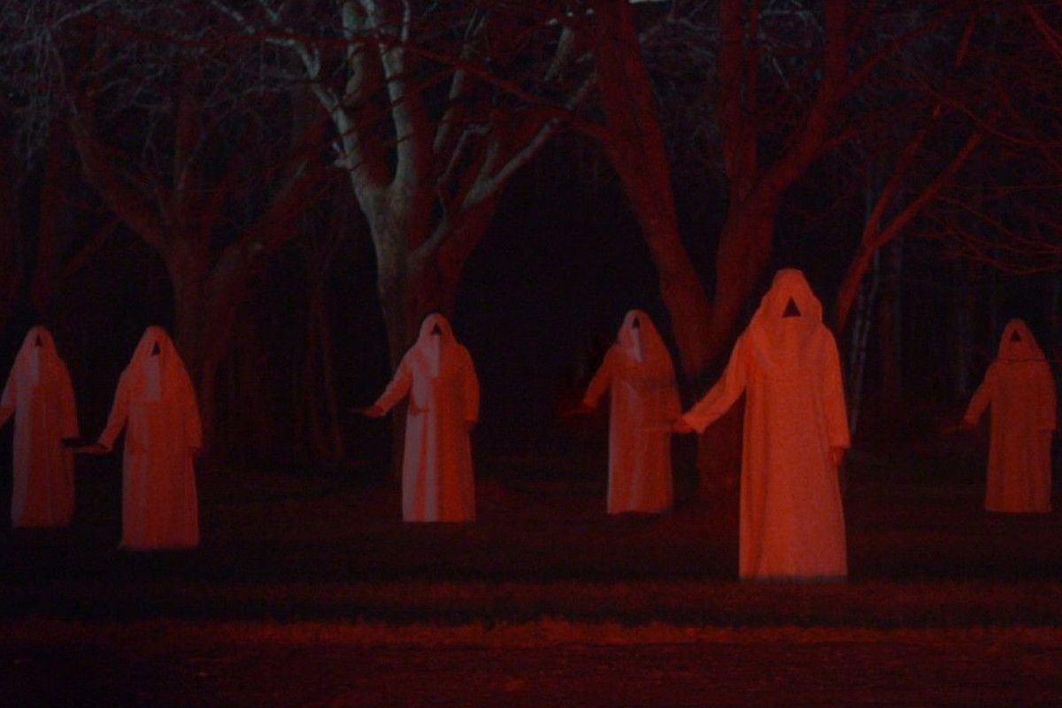 A group of hooded figures holding hands in a forest. - Vampire