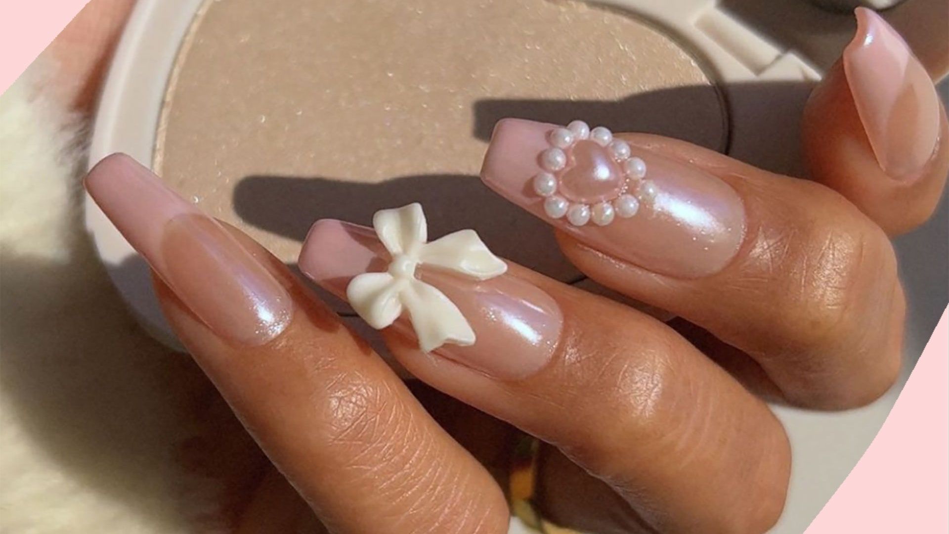 A woman's hand with long, almond-shaped nails painted in pale pink and adorned with white bows and pearls. - Coquette