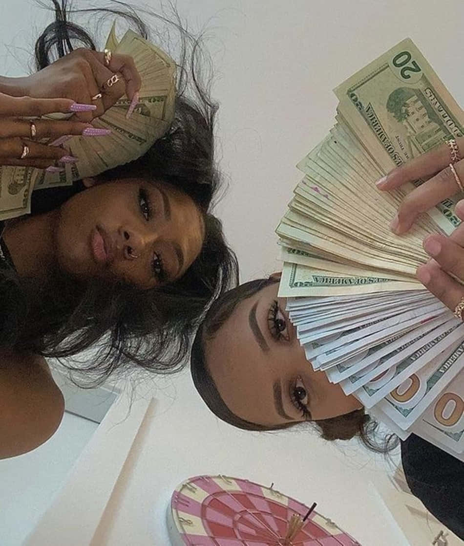 Two women posing with a pile of money. - Money