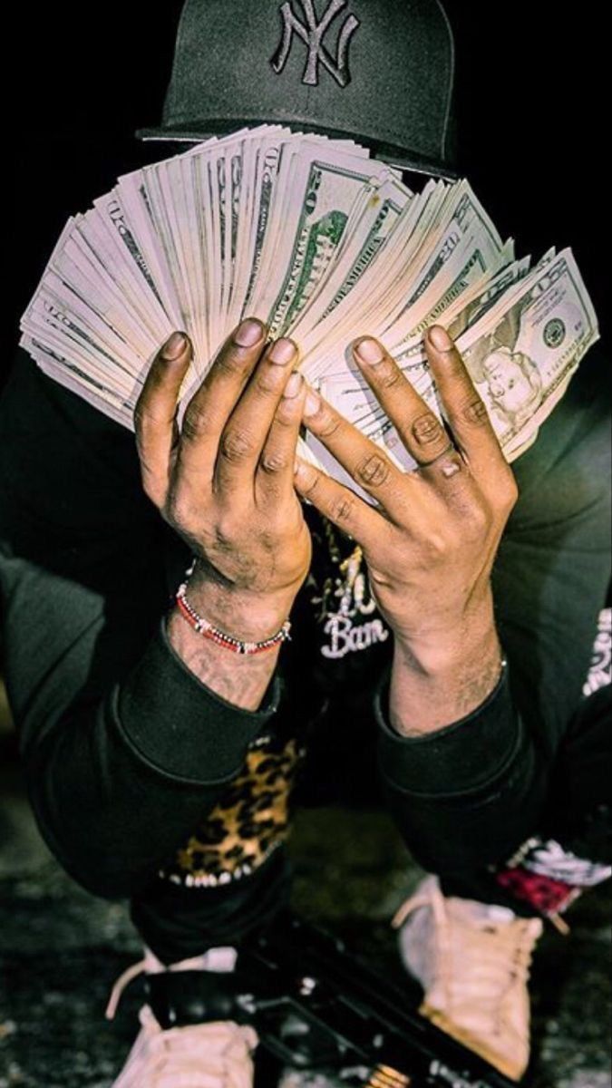 A man holding a stack of money in front of his face. - Money