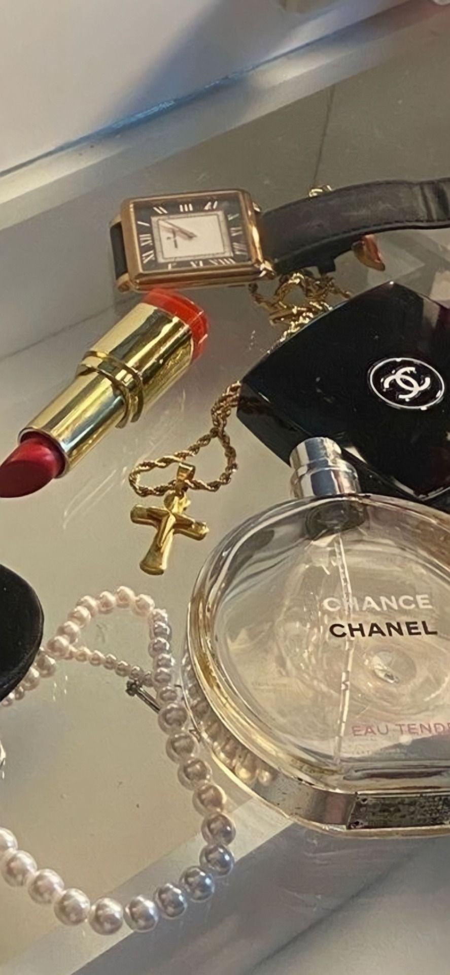 A tray with a watch, lipstick, pearls, and a bottle of Chanel perfume. - Money