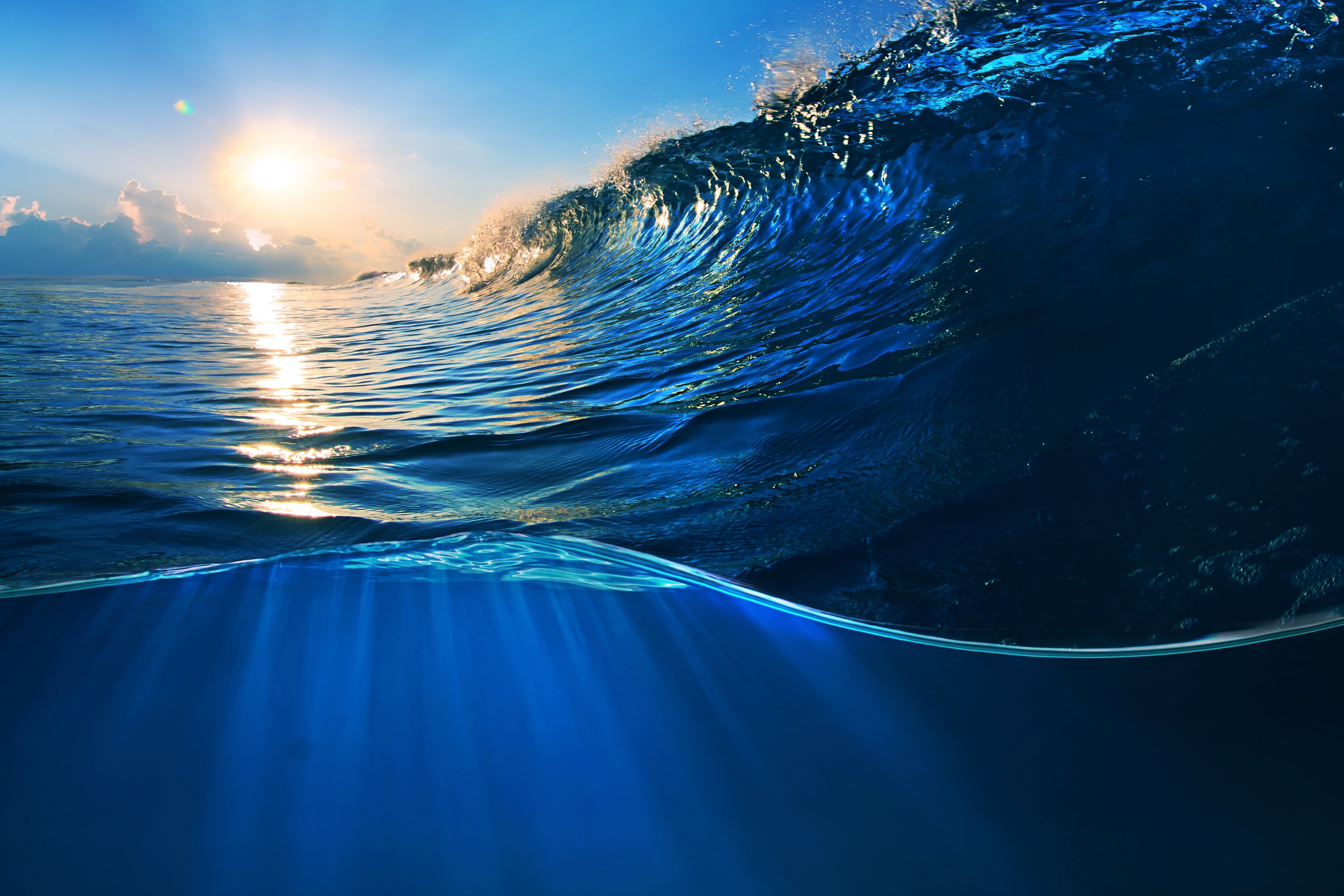 A wave in the ocean with the sun shining on it - Underwater