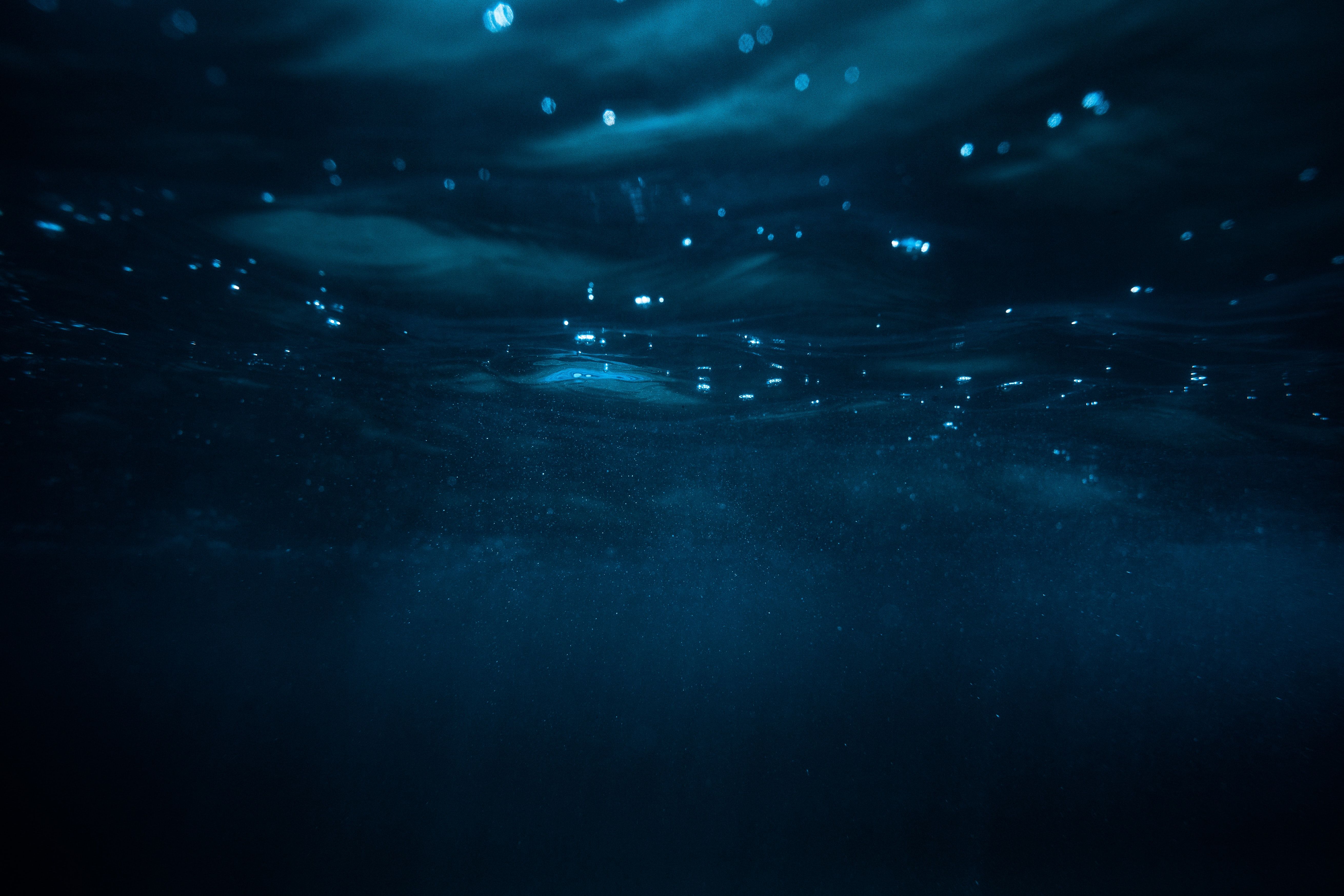 A deep blue ocean with bubbles floating to the surface - Underwater