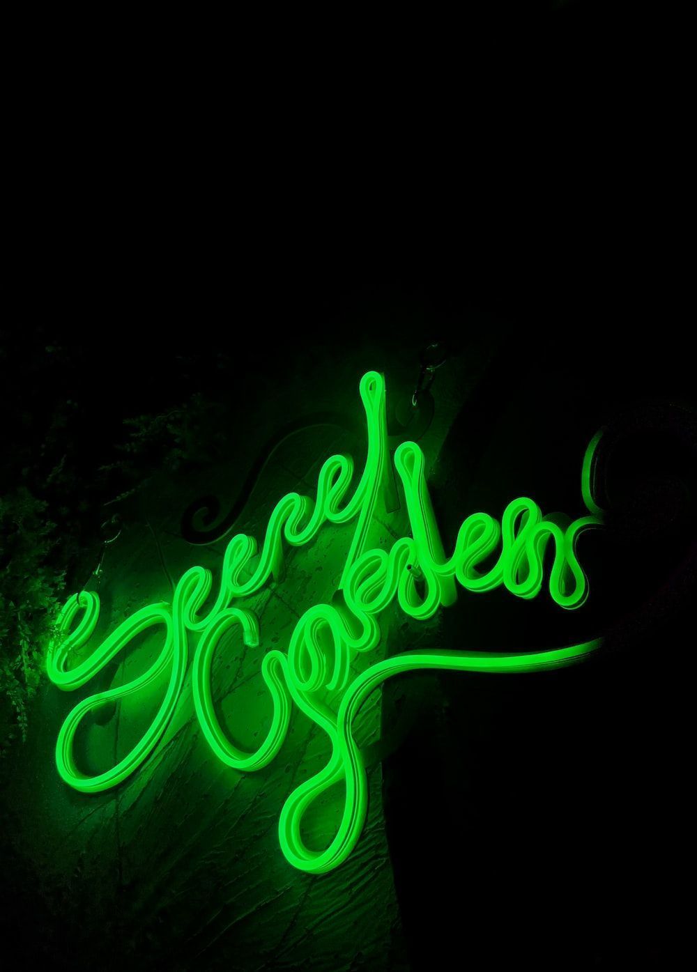 A neon green neon sign on a black wall photo