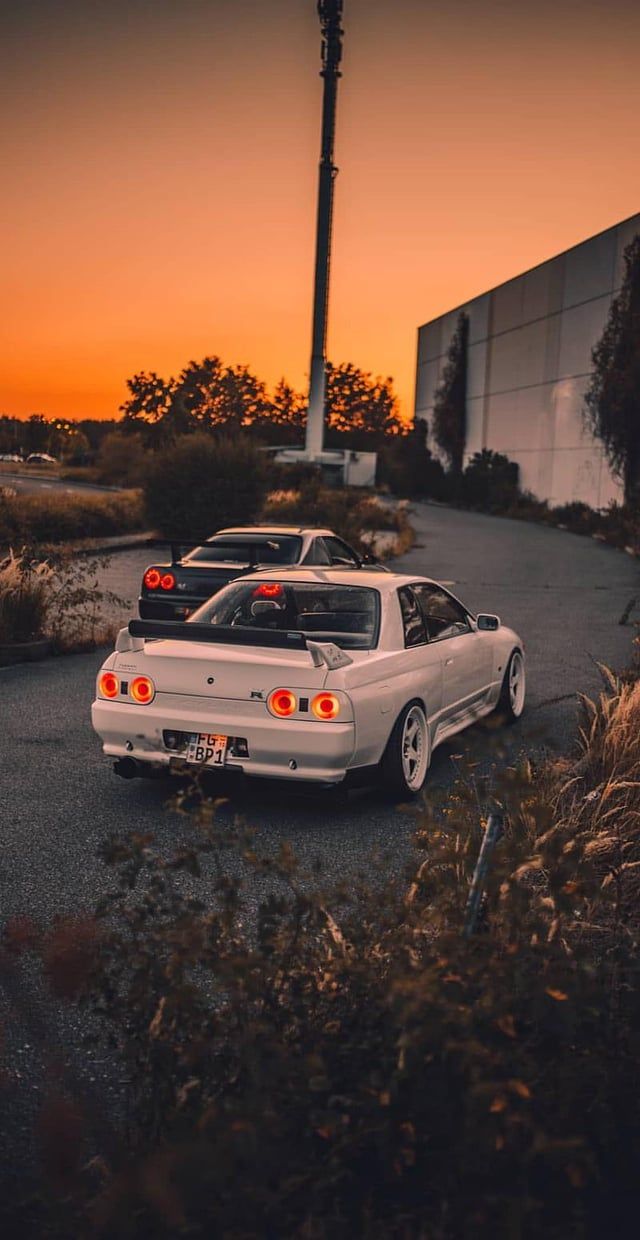 A white car parked in a parking lot at sunset - Nissan Skyline