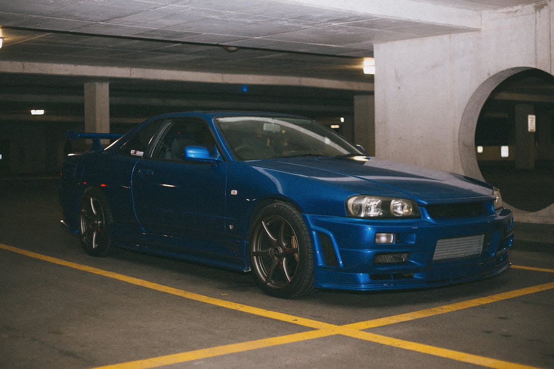 A blue car is parked in a parking garage. - Nissan Skyline