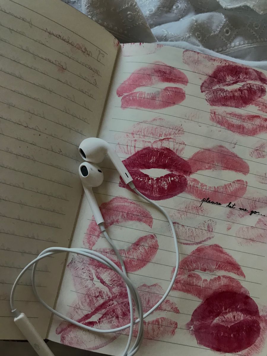 A notebook with lipstick kisses and earphones on top of it. - Lovecore