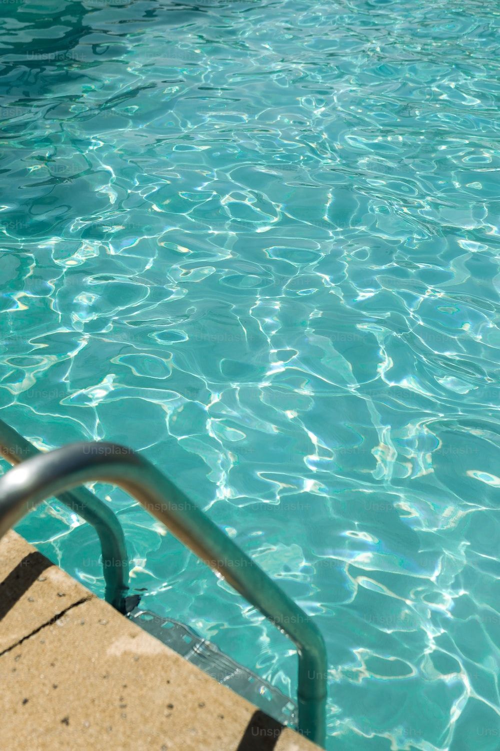 A pool with clear blue water and a metal hand rail photo