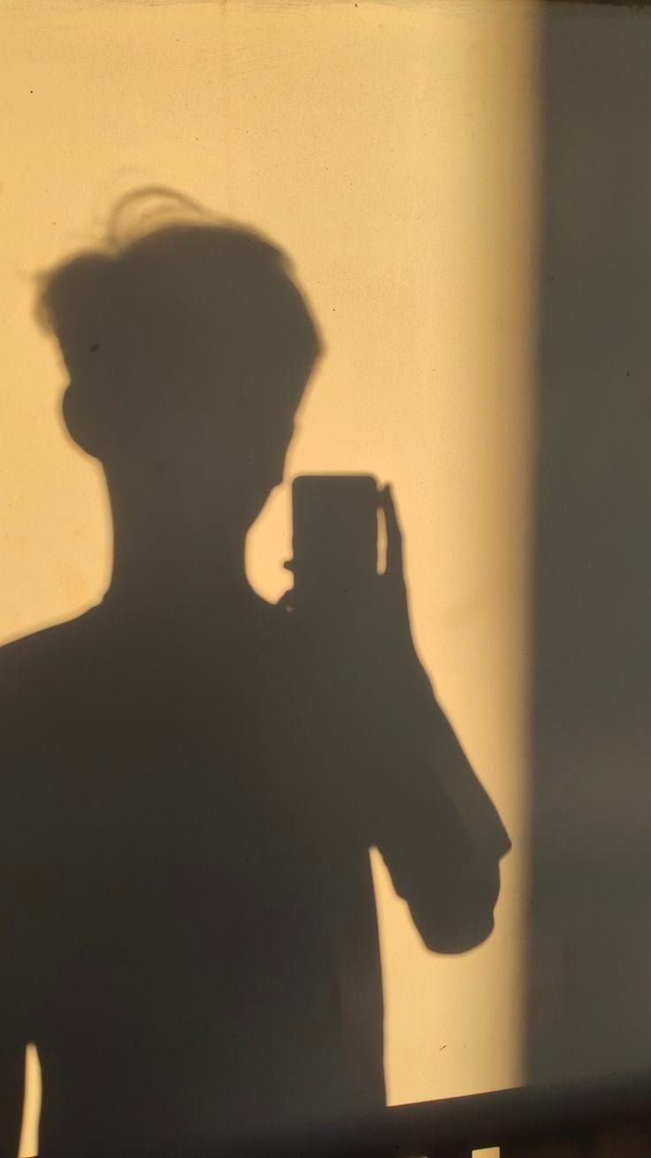 A shadow of a person holding a cell phone. - Shadow